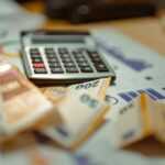 A calculator sitting on top of a pile of money